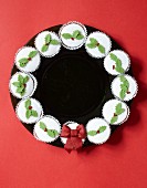 Circle of festively iced cupcakes on black plate
