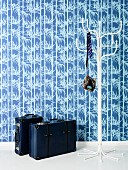 Blue wallpaper, white coat stand and blue leather suitcases