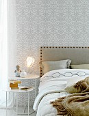 Double bed, white and silver pattern wallpaper and tan details