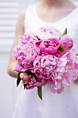 Girl holding bouquet of pink peonies