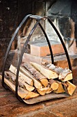 Firewood in curved metal rack in rustic fireplace