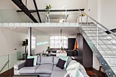 Grey corner sofa and gallery with metal staircase in open-plan, loft-style interior