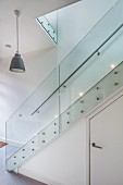 Modern staircase with glass balustrade; storage space with door below