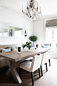 Comfortable dining area with chandelier above solid wood table and simple upholstered furnishings in kitchen-dining room