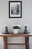 Black and white photo above candle lanterns and potted plant on rustic console table