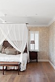 Bedroom with canopy, antique furniture and leaf-patterned wallpaper