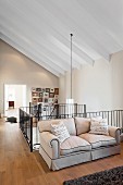 Sofa against metal landing balustrade in open-plan attic interior