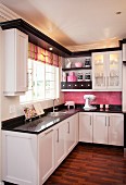 Black and white fitted kitchen with striped Roman blind and pink blackboard splashback