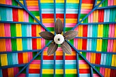 Petal-shaped fan on multi-coloured wooden ceiling