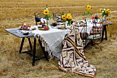 Table set with white linen table cloth and yellow sunflowers in stubbly field