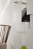 Modern shelving with white screens behind fifties-style armchair