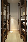 Walk-in wardrobe with dark brown shelves, white cotton storage elements and small standard lamp providing light