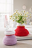 Home-made crocheted vases in purple and red with daisies