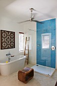 Modernes Hotelbadezimmer mit afrikanischen Accessoires wie geschwungenem Holzhocker und Bild mit geometrischen Mustern