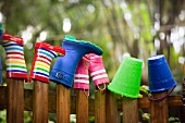 Row of wellington boots and buckets on top of garden fence