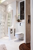 An organically shaped partition wall next to the toilet with spaces for paper and toilet brush in a cosy spa bathroom