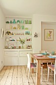 Original kitchen shelving built into niche with collection of 30s vases; wooden table and modern chairs on stripped wooden floor
