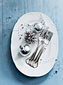 Silver Christmas baubles and forks on serving dish