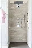 A floor-level, tiled shower with a rain head, a hand-held shower head and wall mounted jets