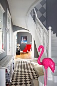 Pink flamingo sculpture at foot of staircase in elegant foyer with view into living room