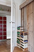 Two stacks of fruit crates for storing toys between board wall and open interior door with view into hallway
