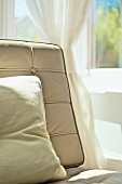 Detail of easy chair backrest with pale, button-tufted leather cover and cushion