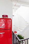 Rot lackierter Retro Kühlschrank und Blick auf Treppenhaus mit weissen Treppenstufen