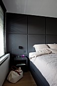 Schlafzimmer mit Doppelbett und dunklen Einbauten, seitlich Fenster mit Jalousien