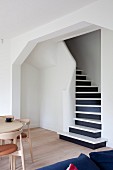 Blick von Wohnraum durch breiten Durchgang auf Treppenaufgang mit schwarz-weissen Stufen