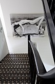 Blick auf Treppenabgang , Teppich mit schwarz-weißem, geometrischem Muster, an Wand grossformatiges Bild