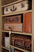 Collection of vintage suitcases and bags on open-fronted shelves