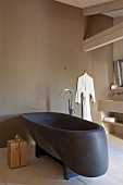 Black designer bathtub and wooden cube side table in purist bathroom