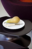 Pear and knife on plate on black side table