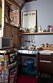 Hob connected to gas bottle and 60s fridge covered in stickers in rustic loft-apartment kitchen