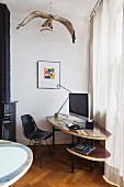 Black, classic-style shell chair at DIY computer desk below stuffed osprey
