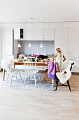 Children at set dining table with black and white kitchen chairs with sheepskin blankets in front of white fitted cupboards