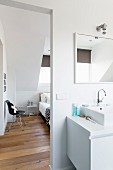 Washstand in bathroom and view of bedroom through open doorway