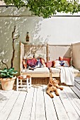 Dog sunbathing on rustic, sunny wooden deck in front of cosy couch with screened sides