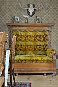 Hunting trophy above magnificent, neoclassical armchair with floral velvet cushions; dining chair backrests in foreground