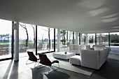 White sofa set in minimalist, elegant interior with panoramic view of autumn landscape