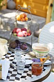 Vintage Etagere mit Früchten, Café au Lait und Honig auf Frühstückstisch im Garten