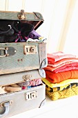 Statt Kleiderschrank: Pulloverstapel neben vollgestopftem Vintage Koffer