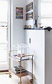Retro serving trolley against half-height partition decorated with colourful figurines
