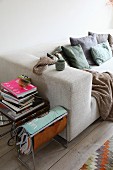 Sofa with many scatter cushions, magazine rack and books on side table