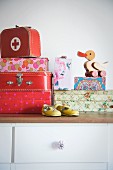 Set of children's suitcases, wooden duck on boxes and child's shoes on chest of drawers