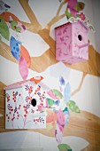 Painted nesting boxes hung on wall with tree mural
