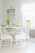 White-painted, wooden furniture in shabby-chic dining area in kitchen-dining room
