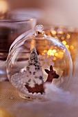 Transparent Christmas tree bauble with deer and Christmas tree figures inside decorating table (close-up)
