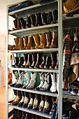 Collection of cowboy boots, leather jacket and cowboy hat on metal shelves in hallway