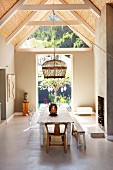 Rustic dining area and wicker pendant lamp below exposed roof structure with bamboo interior cladding